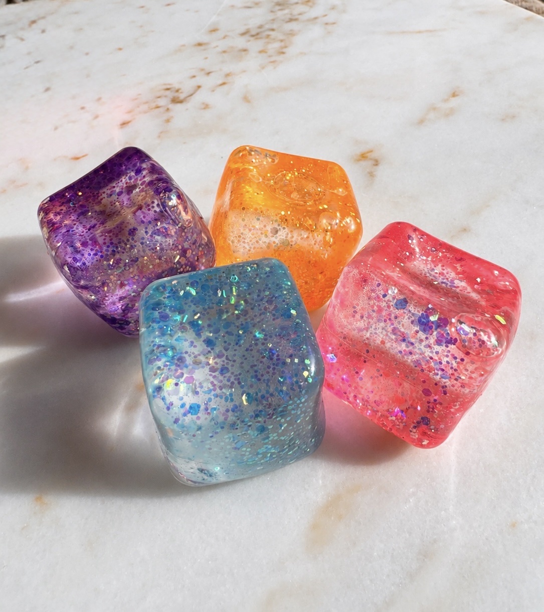Four colourful glitter cube squishies